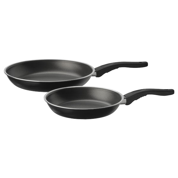 Two black non-stick frying pans with handles, one large and one small, placed side by side.